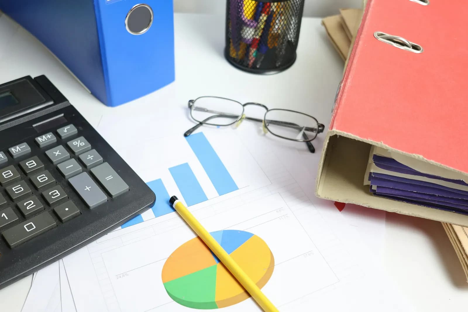 Desk with a calculator, folders and printed charts